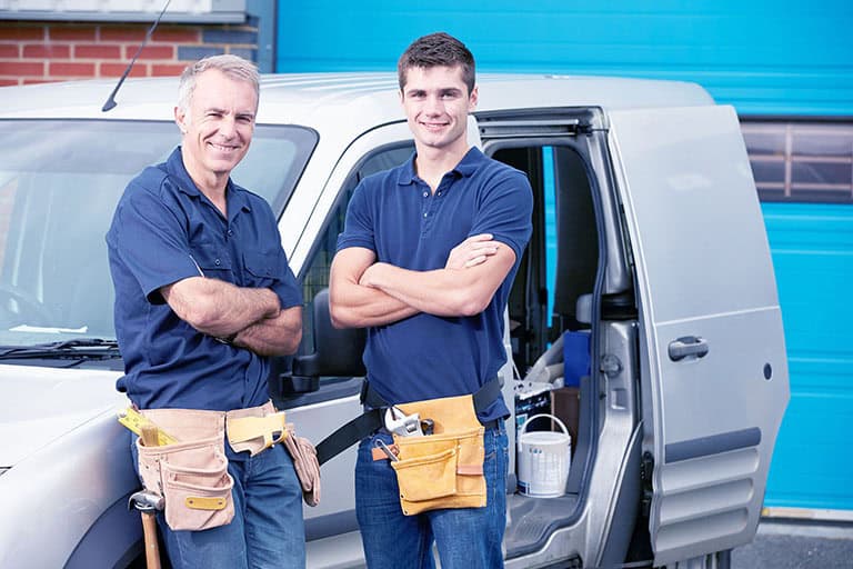 Workers In Family Business Standing Next To Van