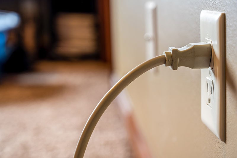 White Power Cord Plugged Into A White Wall Outlet