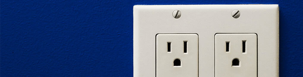 two three-prong outlets on a blue wall