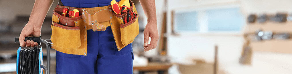 electrician with a toolbelt standing indoors